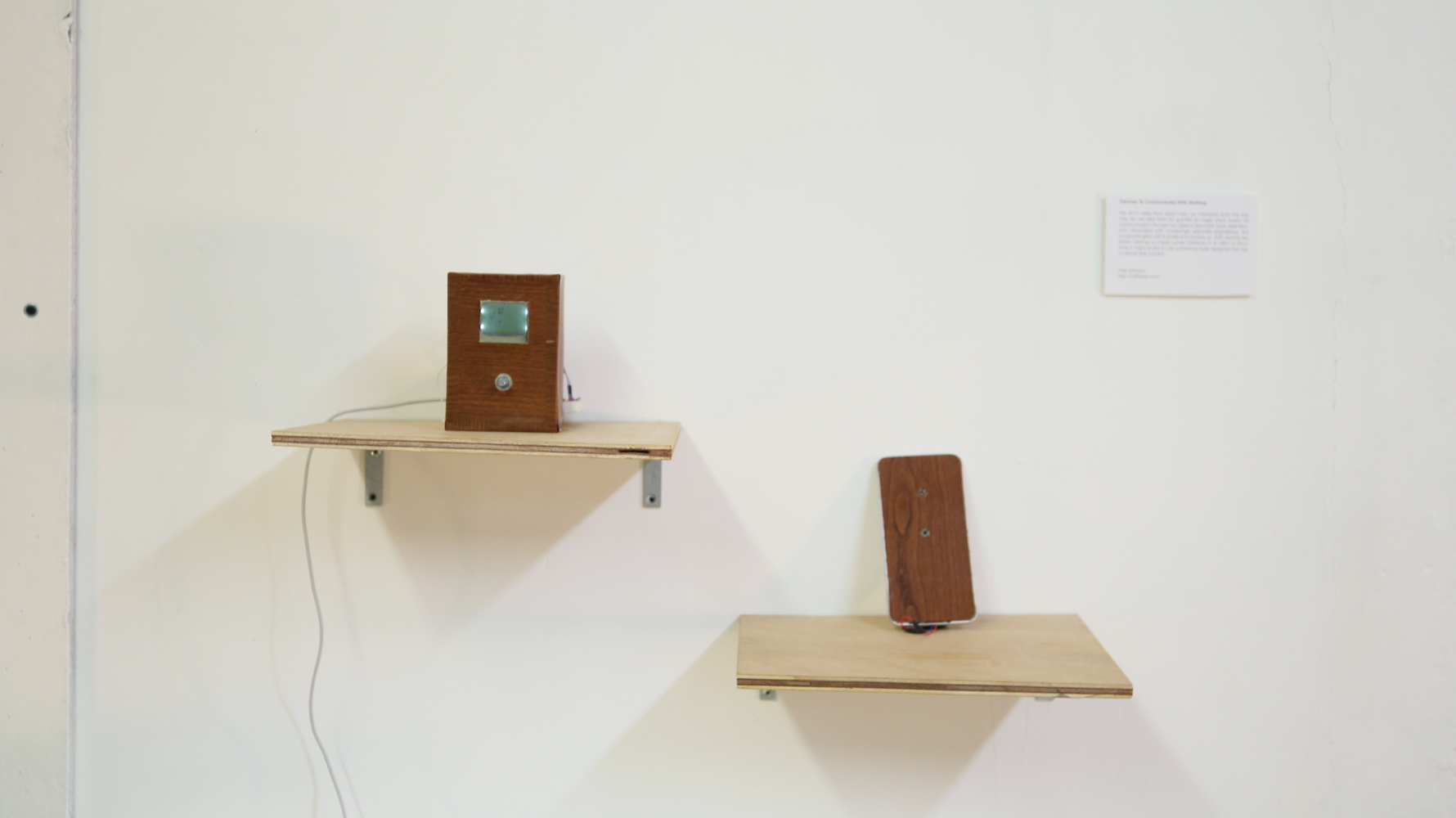 Two shelves on a gallery wall each holding a device