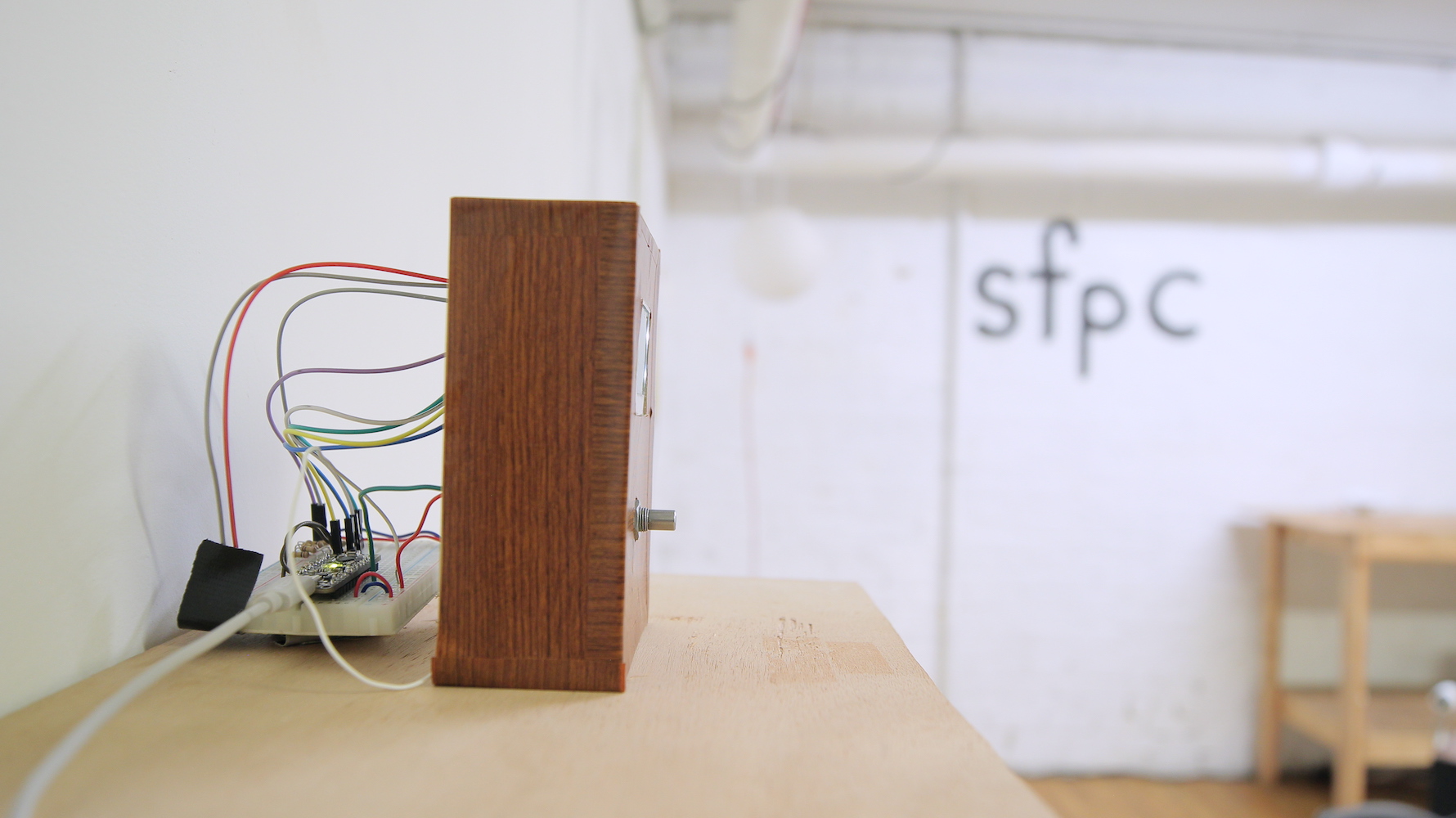 Device side view showing exposed wires, a breadboard and Arduino behind